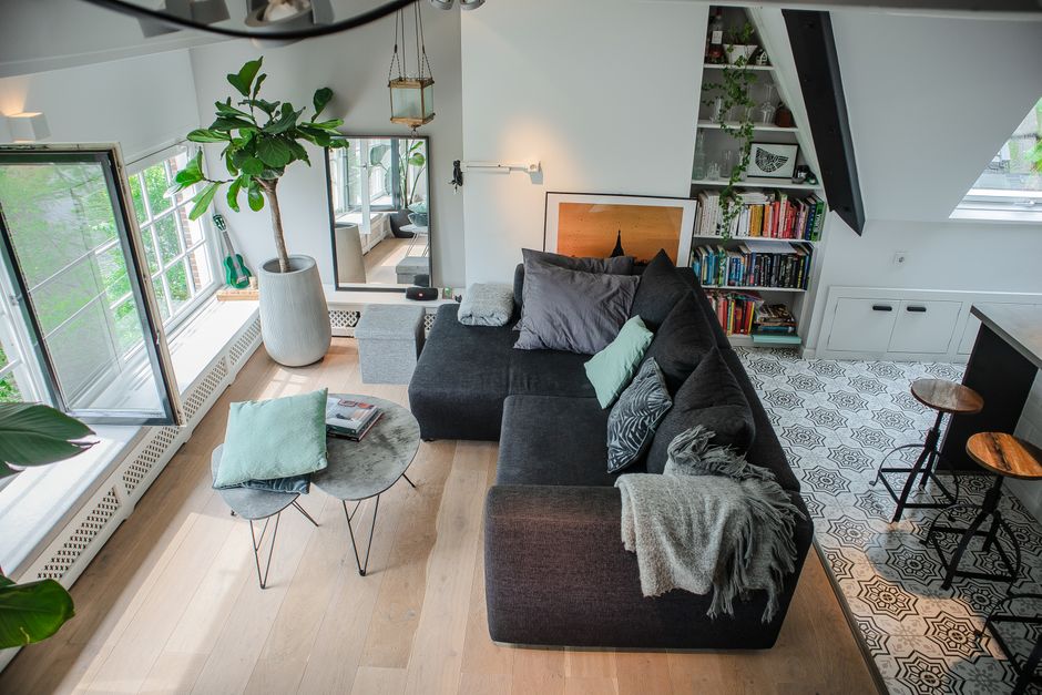 Bright and stylish modern living room with large sofa, plants, and natural lighting.